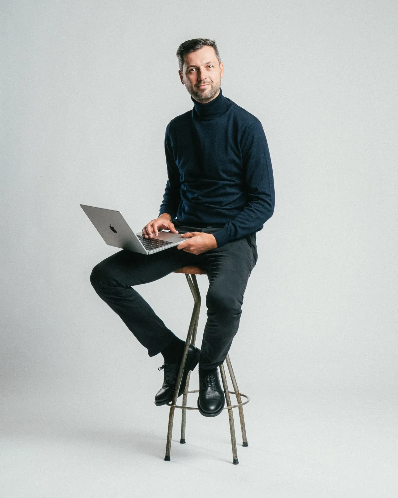 Aleks Jakobsons, founder of Heartwood, sitting on a stool working on a laptop